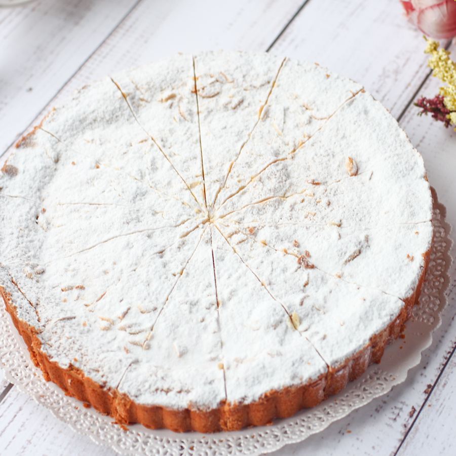 Основа торта из песочного теста, начинка из заварного ванильного крема с легкими цитрусовыми нотками. Сверху торт украшен колотыми орешками итальянской сосны - пинии и присыпан пудрой. изображение 2