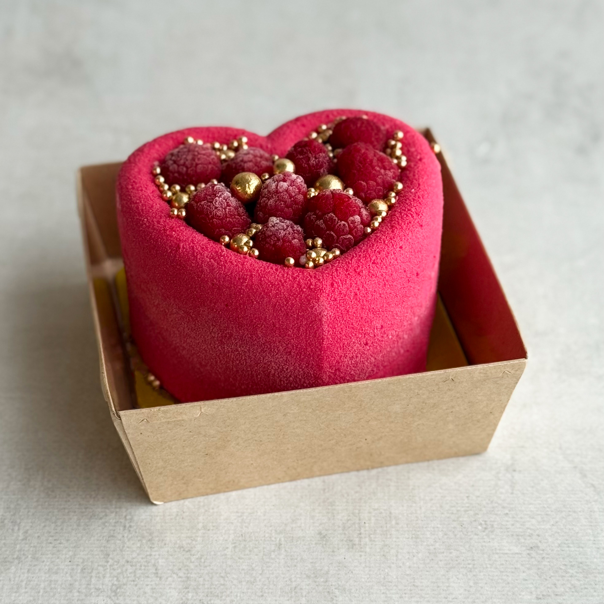 Бенто-торт Праздничный (Сердце с малиной) в индивид.упаковке. Нежный муссовый бенто-торт в форме сердца с начинкой из ананасового конфитюра с кусочками ананаса на тонкой бисквитной подложке. Торт украшен спелыми ягодами малины и золотым декором. изображение 1