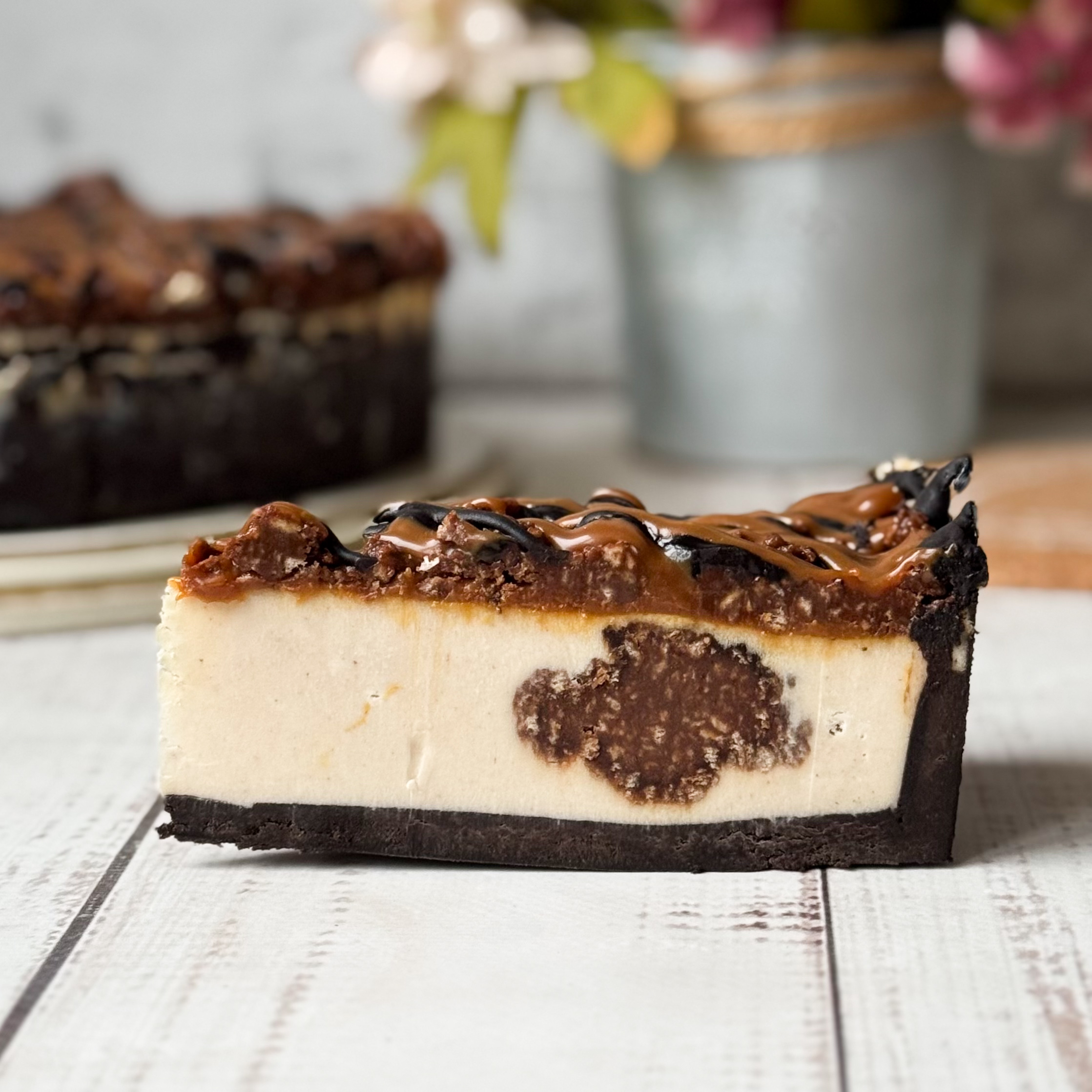 Классический сливочно-сырный чизкейк Нью-Йорк на подложке из песочного шоколадного теста с начинкой из шоколадного ганаша и карамельного кранча. Сверху чизкейк украшен карамельным кранчем, арахисом, карамелью и шоколадным муссом. изображение 1