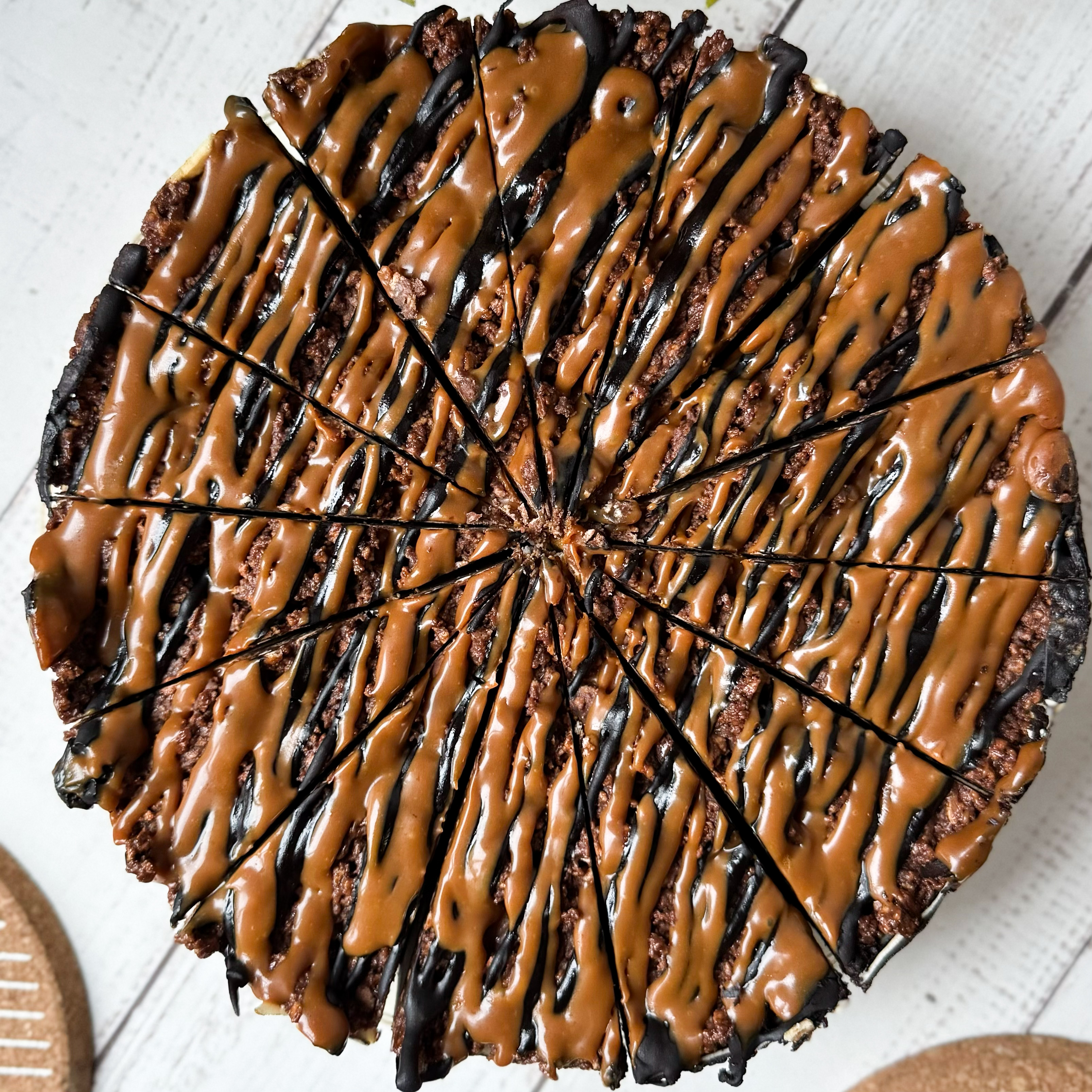 Классический сливочно-сырный чизкейк Нью-Йорк на подложке из песочного шоколадного теста с начинкой из шоколадного ганаша и карамельного кранча. Сверху чизкейк украшен карамельным кранчем, арахисом, карамелью и шоколадным муссом. изображение 10