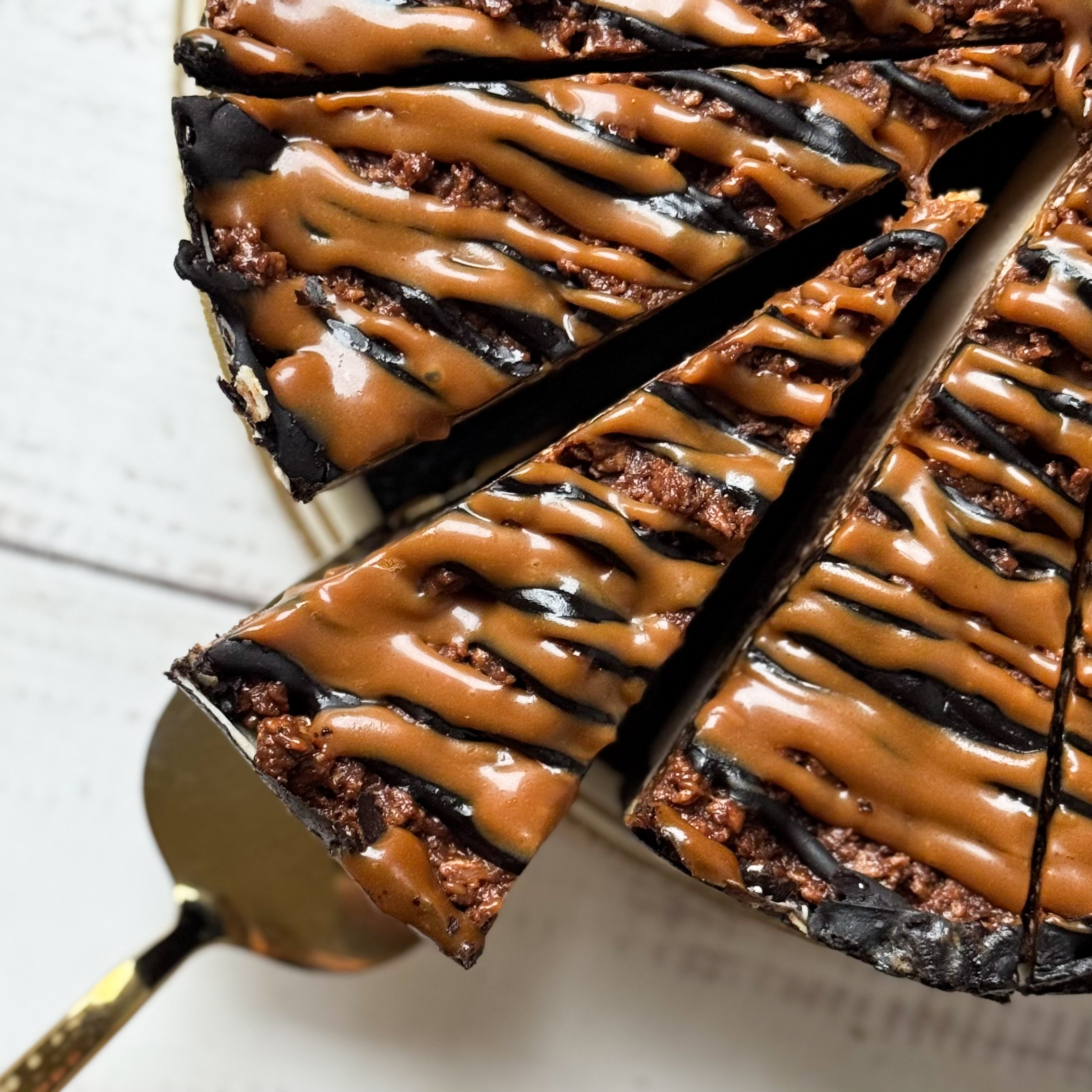 Классический сливочно-сырный чизкейк Нью-Йорк на подложке из песочного шоколадного теста с начинкой из шоколадного ганаша и карамельного кранча. Сверху чизкейк украшен карамельным кранчем, арахисом, карамелью и шоколадным муссом. изображение 4