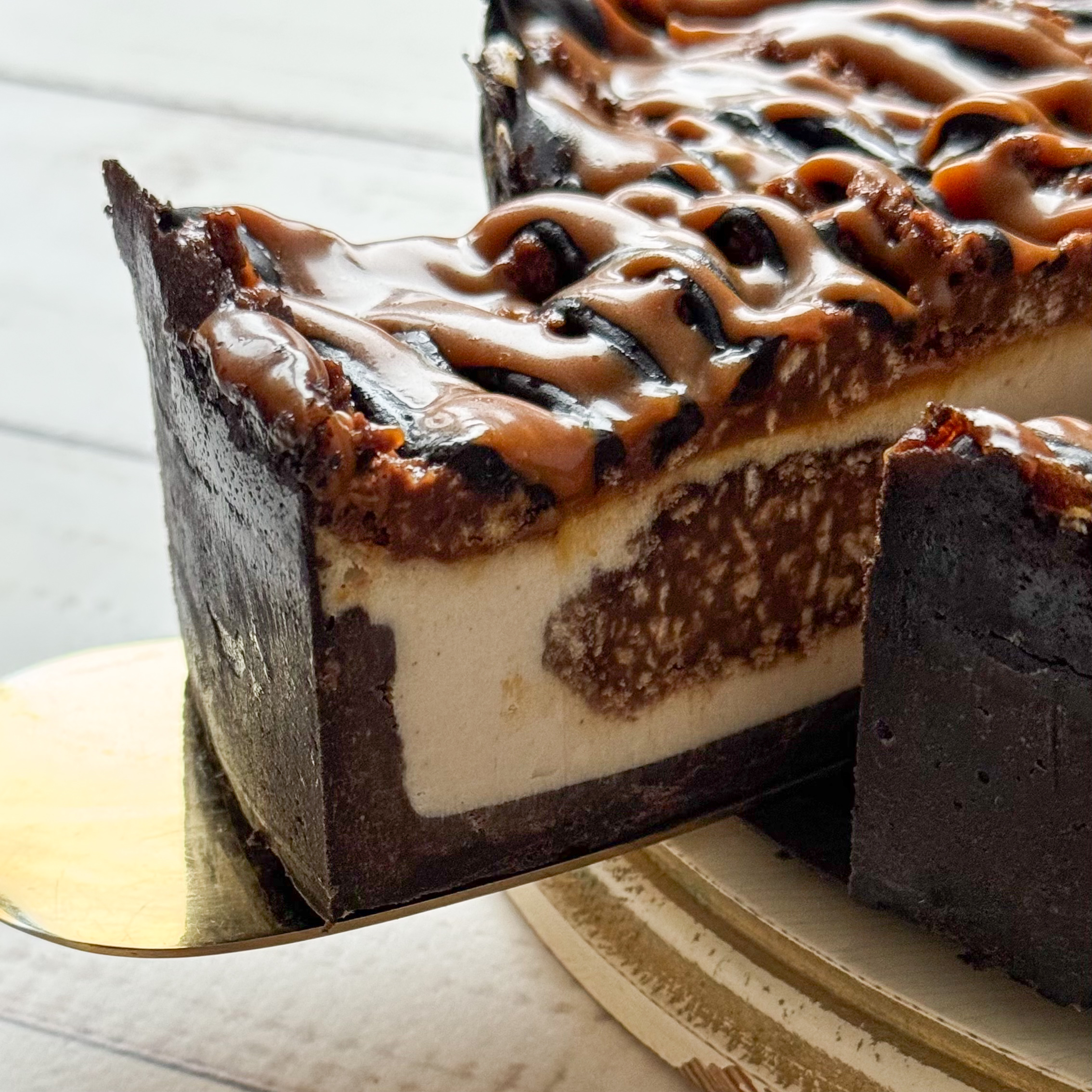 Классический сливочно-сырный чизкейк Нью-Йорк на подложке из песочного шоколадного теста с начинкой из шоколадного ганаша и карамельного кранча. Сверху чизкейк украшен карамельным кранчем, арахисом, карамелью и шоколадным муссом. изображение 6