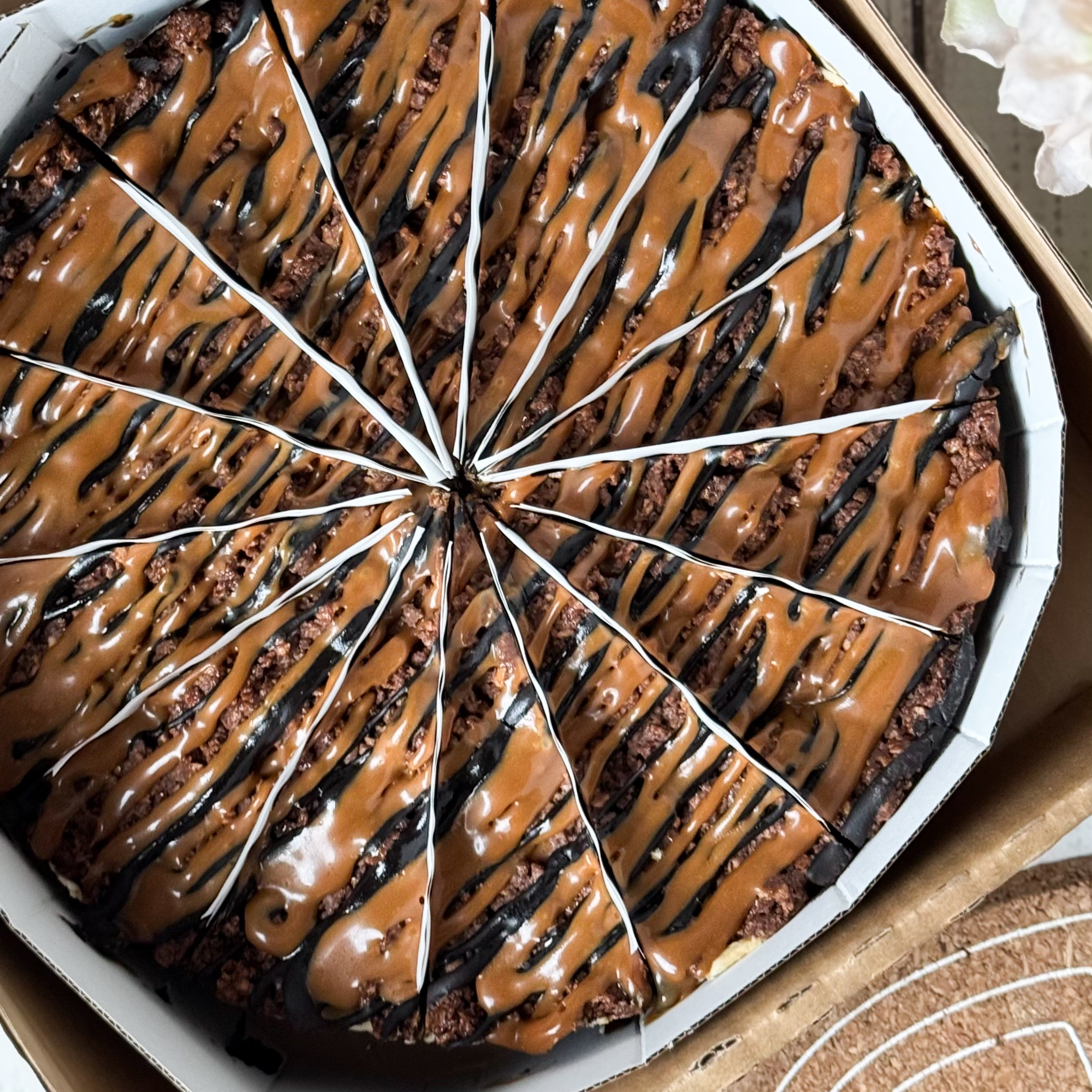 Классический сливочно-сырный чизкейк Нью-Йорк на подложке из песочного шоколадного теста с начинкой из шоколадного ганаша и карамельного кранча. Сверху чизкейк украшен карамельным кранчем, арахисом, карамелью и шоколадным муссом. изображение 8