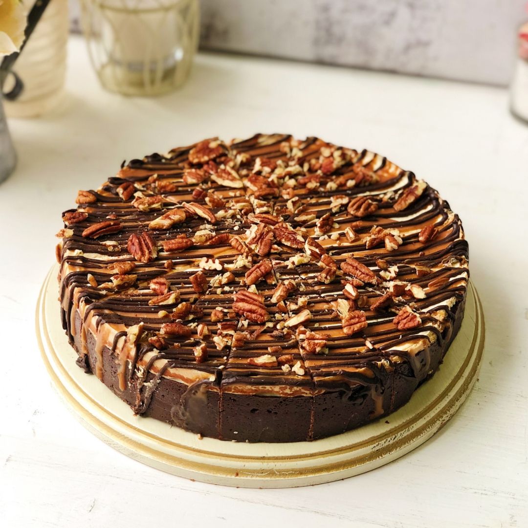 Классический чизкейк Нью-Йорк с шоколадными криспами на песочно-шоколадной основе. Сверху чизкейк залит карамелью и шоколадом, а также усыпан дробленым грецким орехом изображение 3