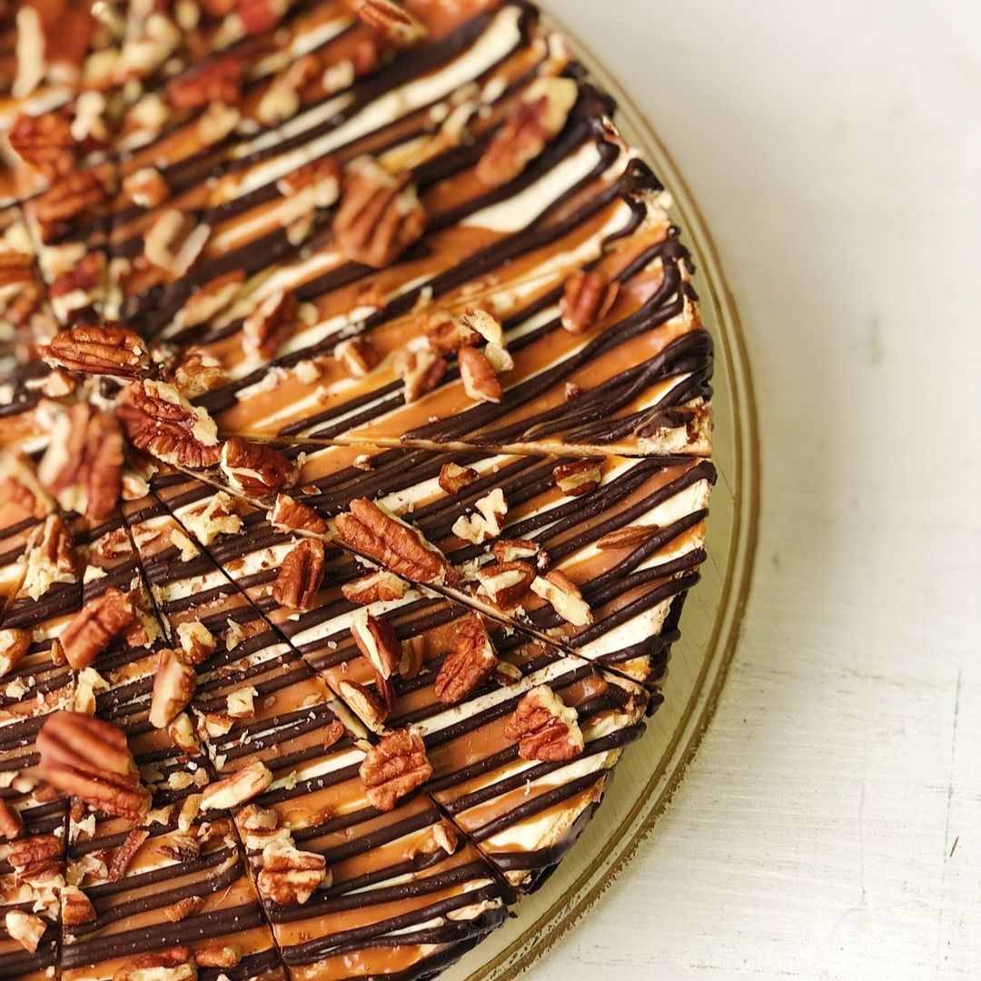 Классический чизкейк Нью-Йорк с шоколадными криспами на песочно-шоколадной основе. Сверху чизкейк залит карамелью и шоколадом, а также усыпан дробленым грецким орехом изображение 4