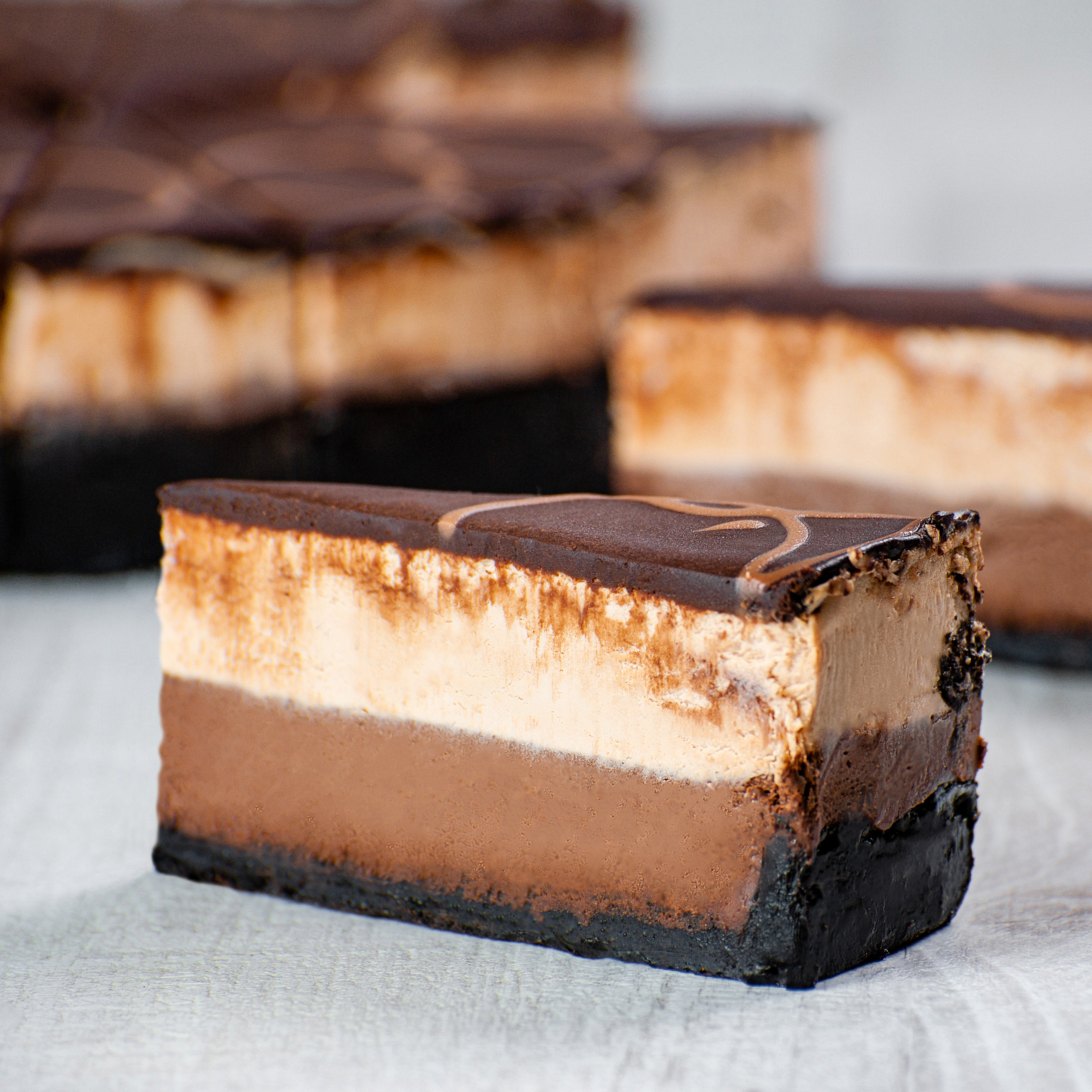 Корж из темного шоколада, горько-сладкий шоколадный чизкейк, чизкейк из молочного шоколада. Украшен глазурью из темного шоколада и полит молочным шоколадом. изображение 1