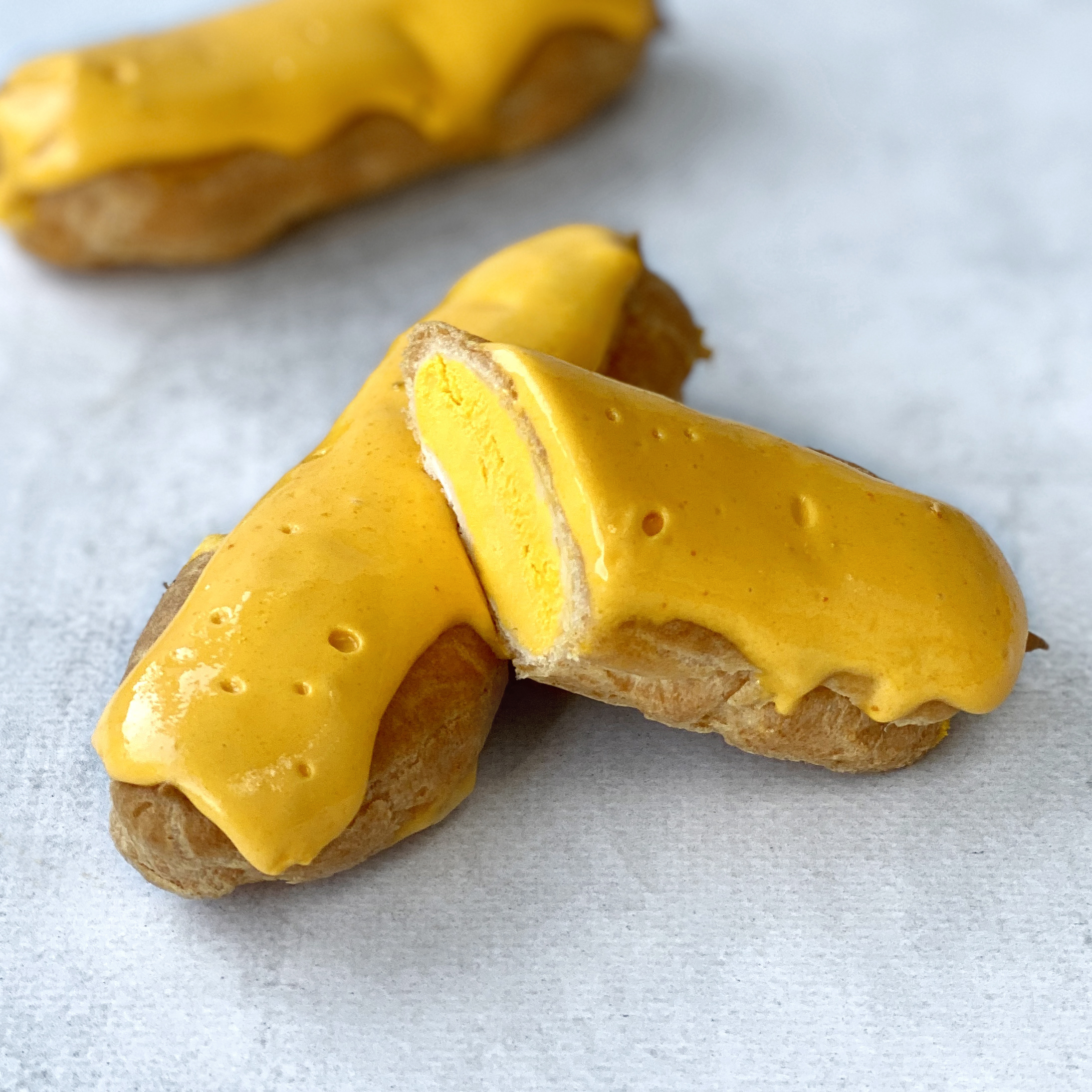 Эклер с начинкой из пюре маракуйи, манго и кремом из взбитых сливок, покрытый помадкой с тропическим вкусом изображение 1