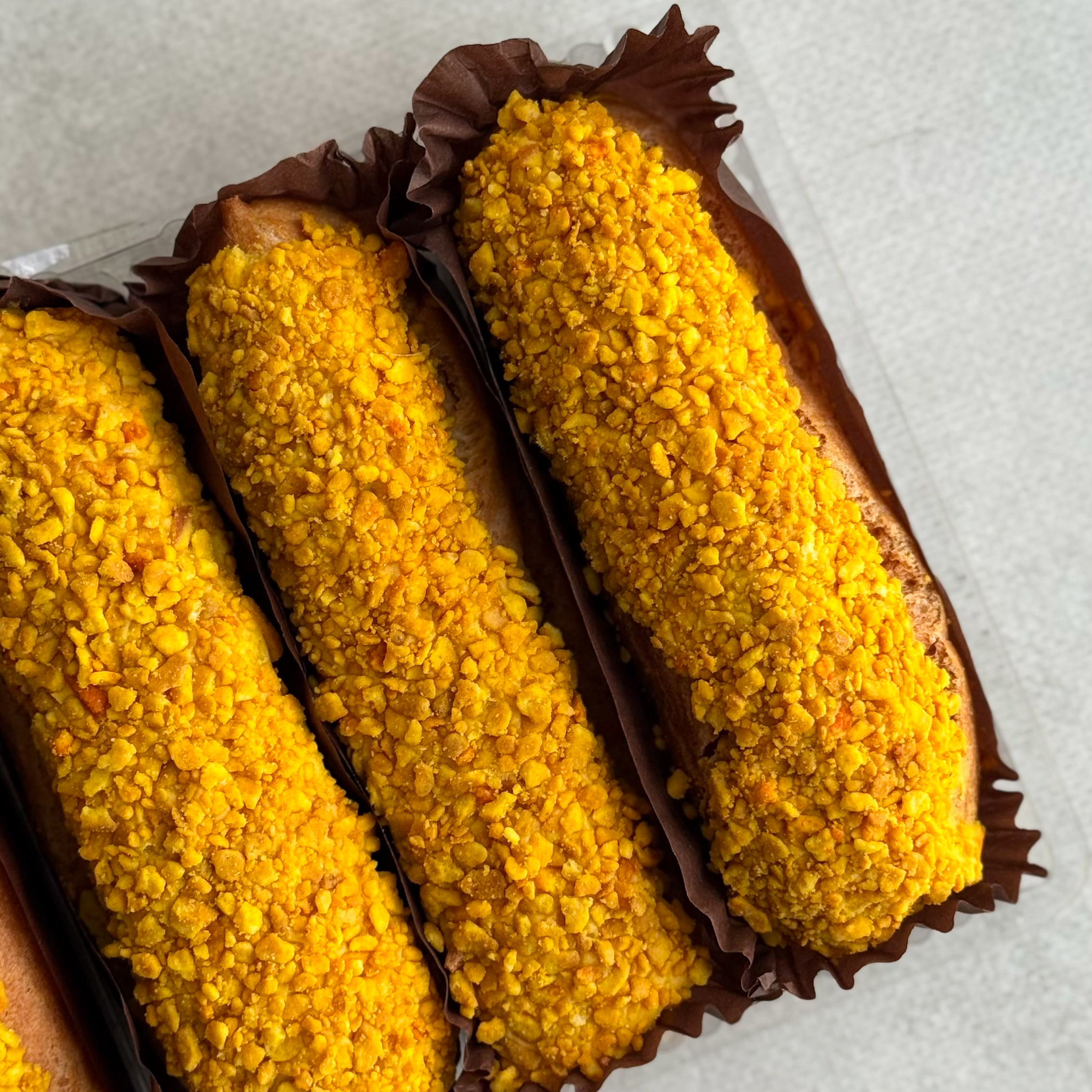 Эклер с начинкой из пюре маракуйи, манго и кремом из взбитых сливок, покрытый помадкой и посыпкой с тропическим вкусом изображение 3