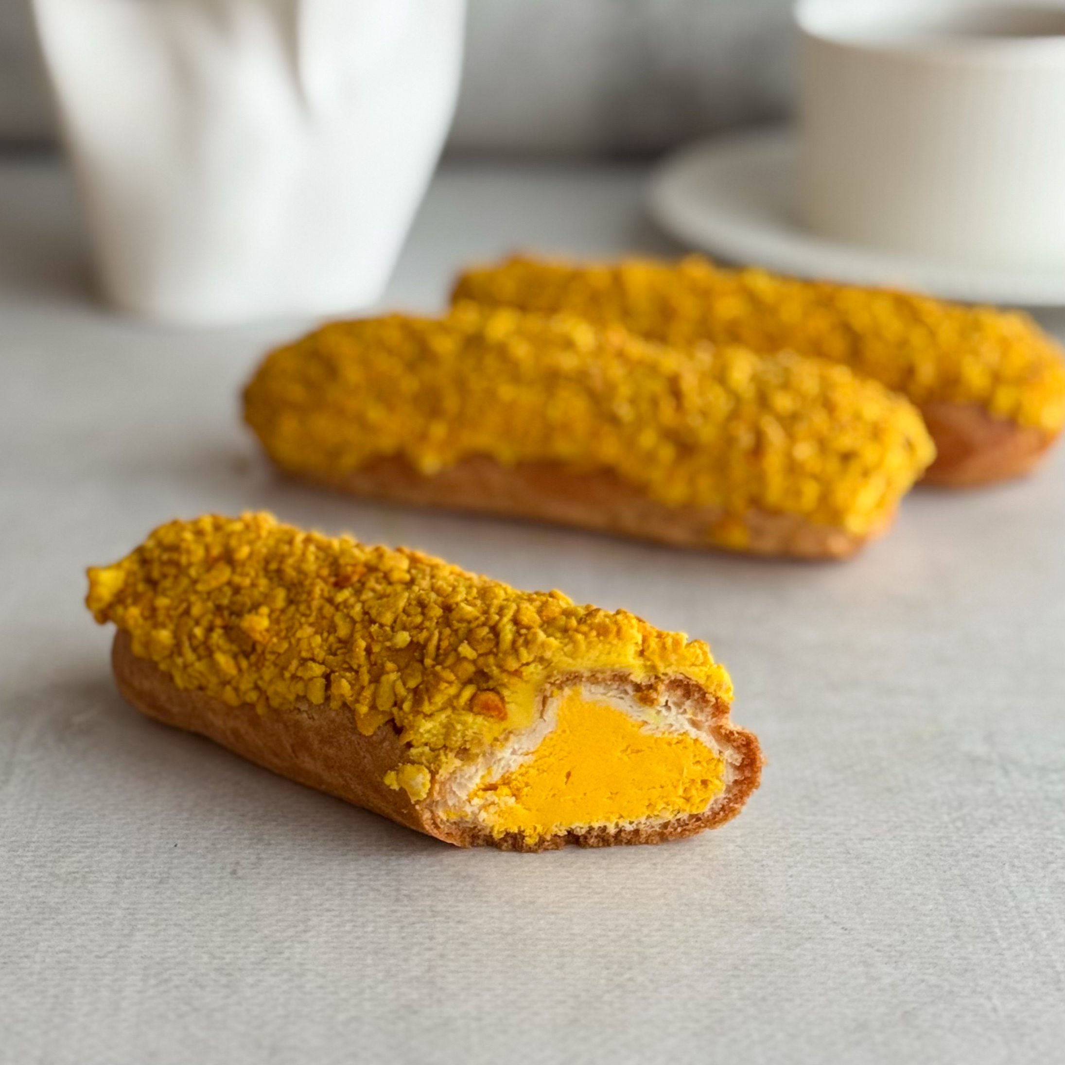 Эклер с начинкой из пюре маракуйи, манго и кремом из взбитых сливок, покрытый помадкой и посыпкой с тропическим вкусом изображение 4