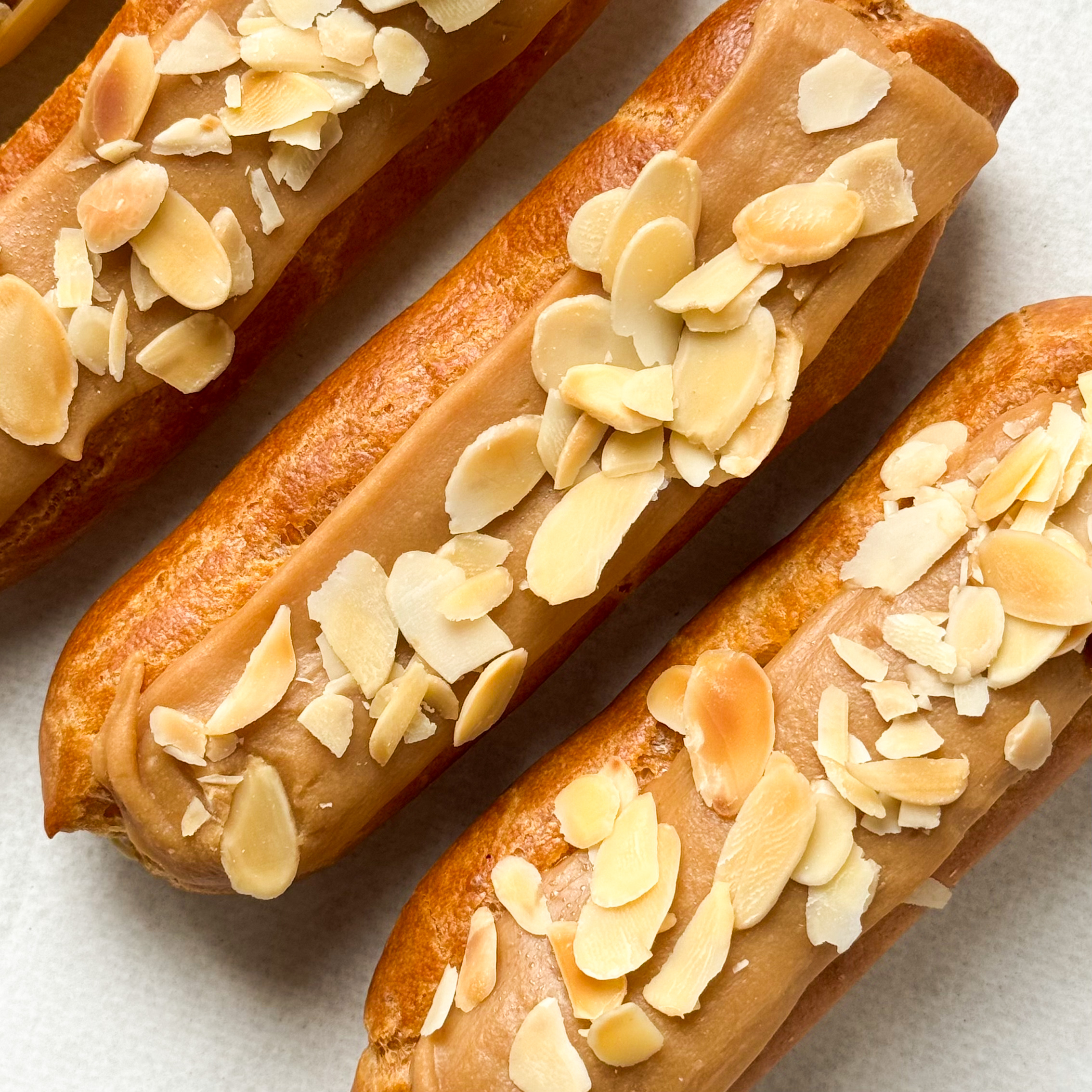 Карамельный эклер с кремом из взбитых сливок с карамелью, украшенный лепестками миндаля изображение 4