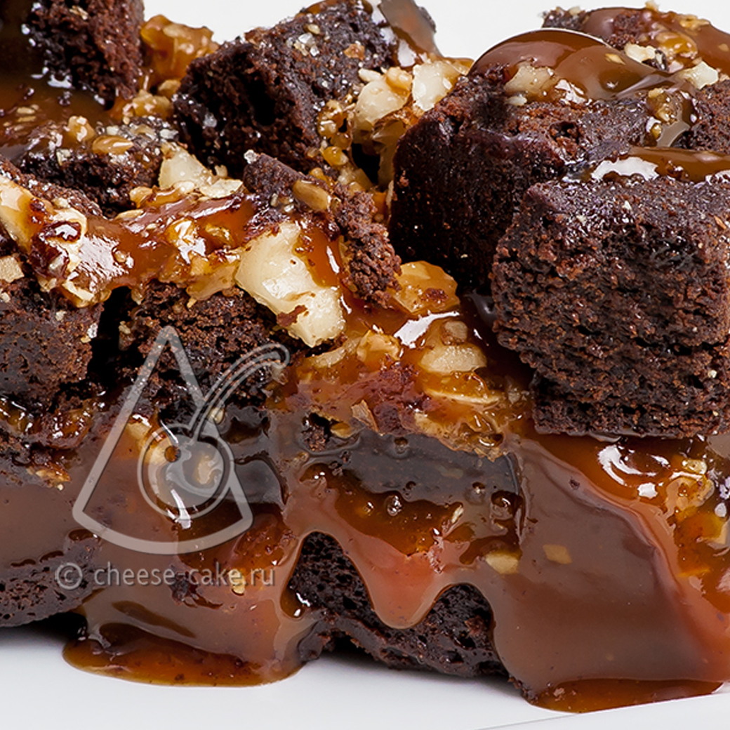 Два слоя сочного шоколадного брауни, пропитанные густой карамелью, сверху украшены засахаренными кусочками брауни и грецкими орехами. изображение 2