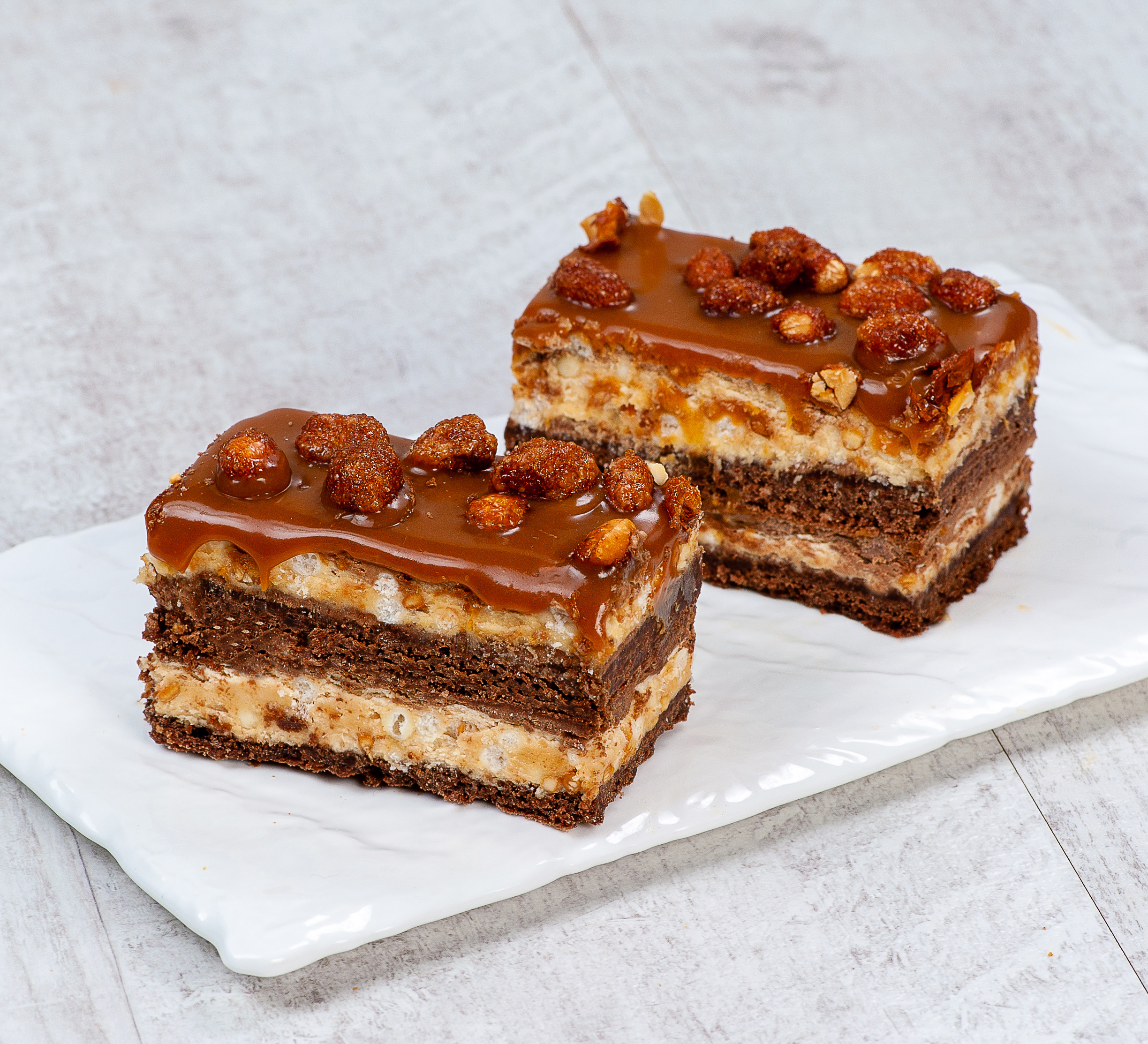 Классический брауни со слоями сливочной карамели, пралине и молочного шоколада. Сверху пирожное украшено карамелизированным арахисом и залит плотным слоем мягкой карамели изображение 3