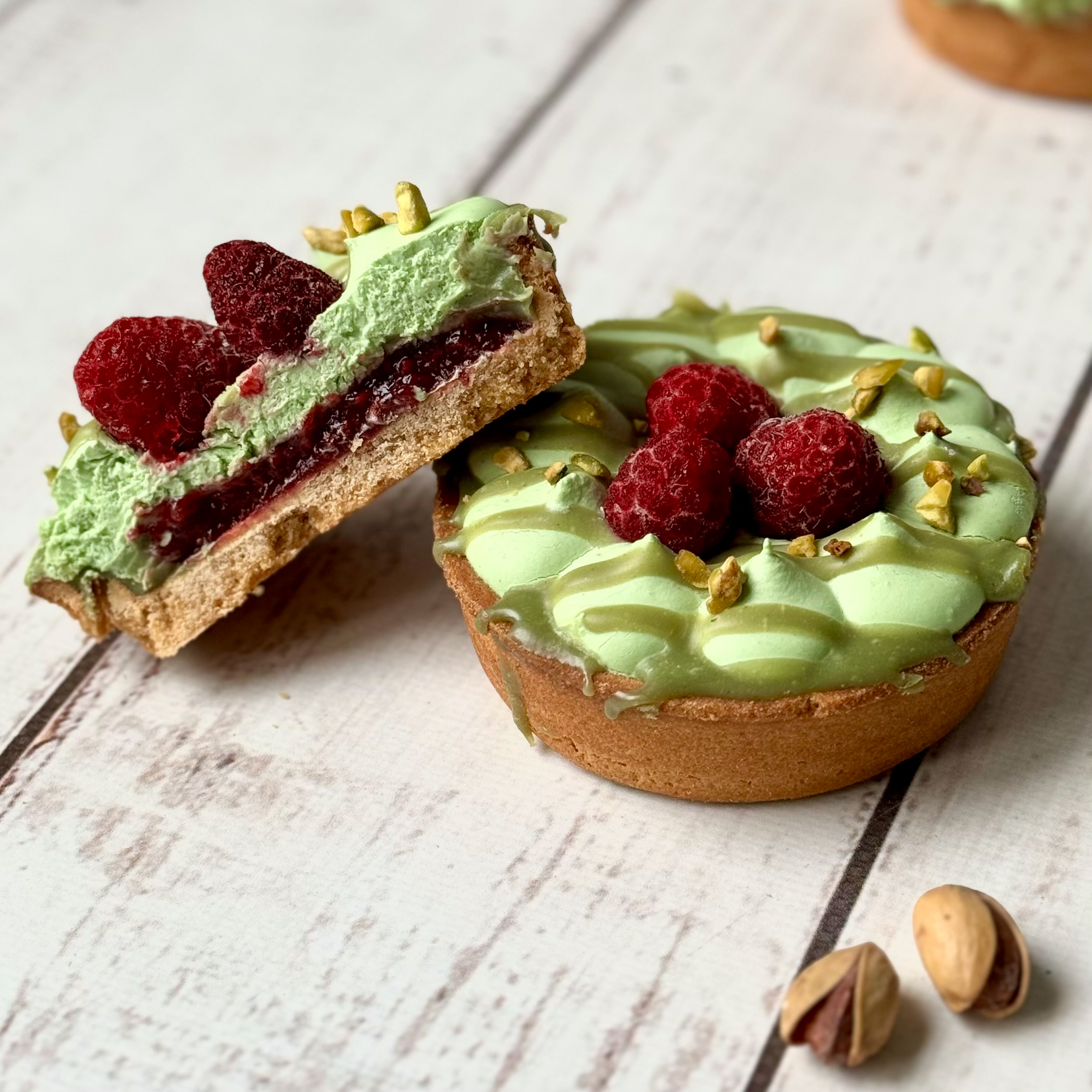 Фисташковый крем, малиновая прослойка в корзиночке из песочного теста. Сверху тарталетка украшена ягодами малины и дроблёной фисташкой. изображение 1