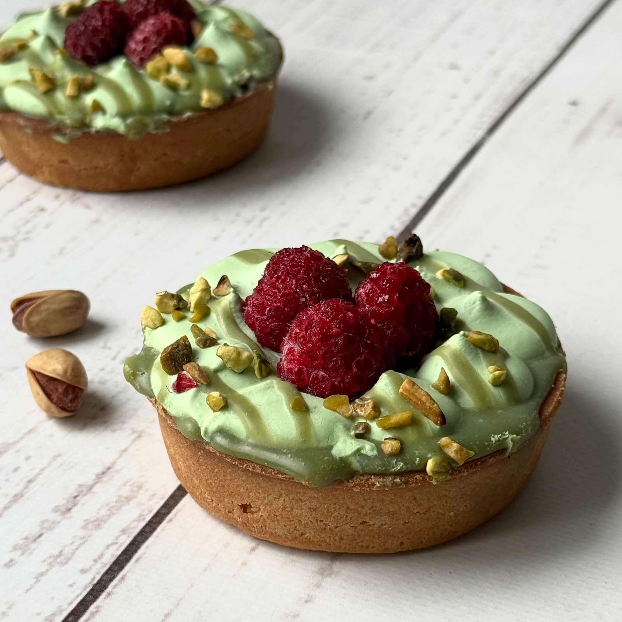 Фисташковый крем, малиновая прослойка в корзиночке из песочного теста. Сверху тарталетка украшена ягодами малины и дроблёной фисташкой. изображение 2