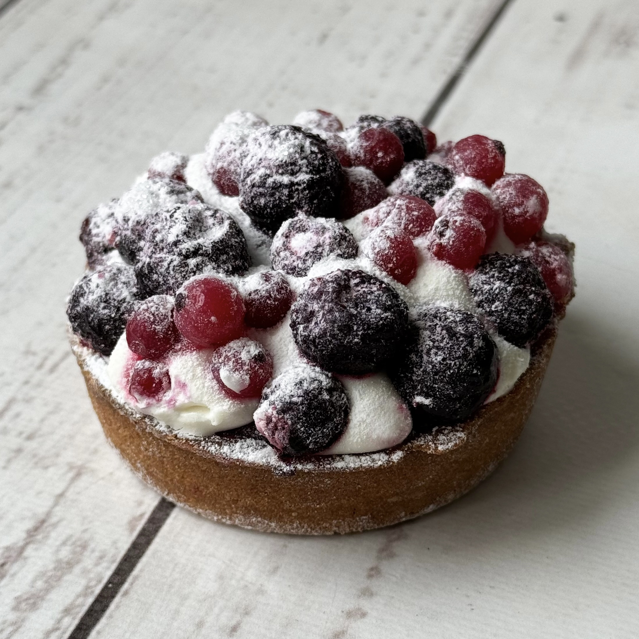 Ягодная тарталетка с начинкой из пюре чёрной смородины, взбитыми сливками и ягодами чёрной смородины в корзиночке из песочного теста. изображение 1