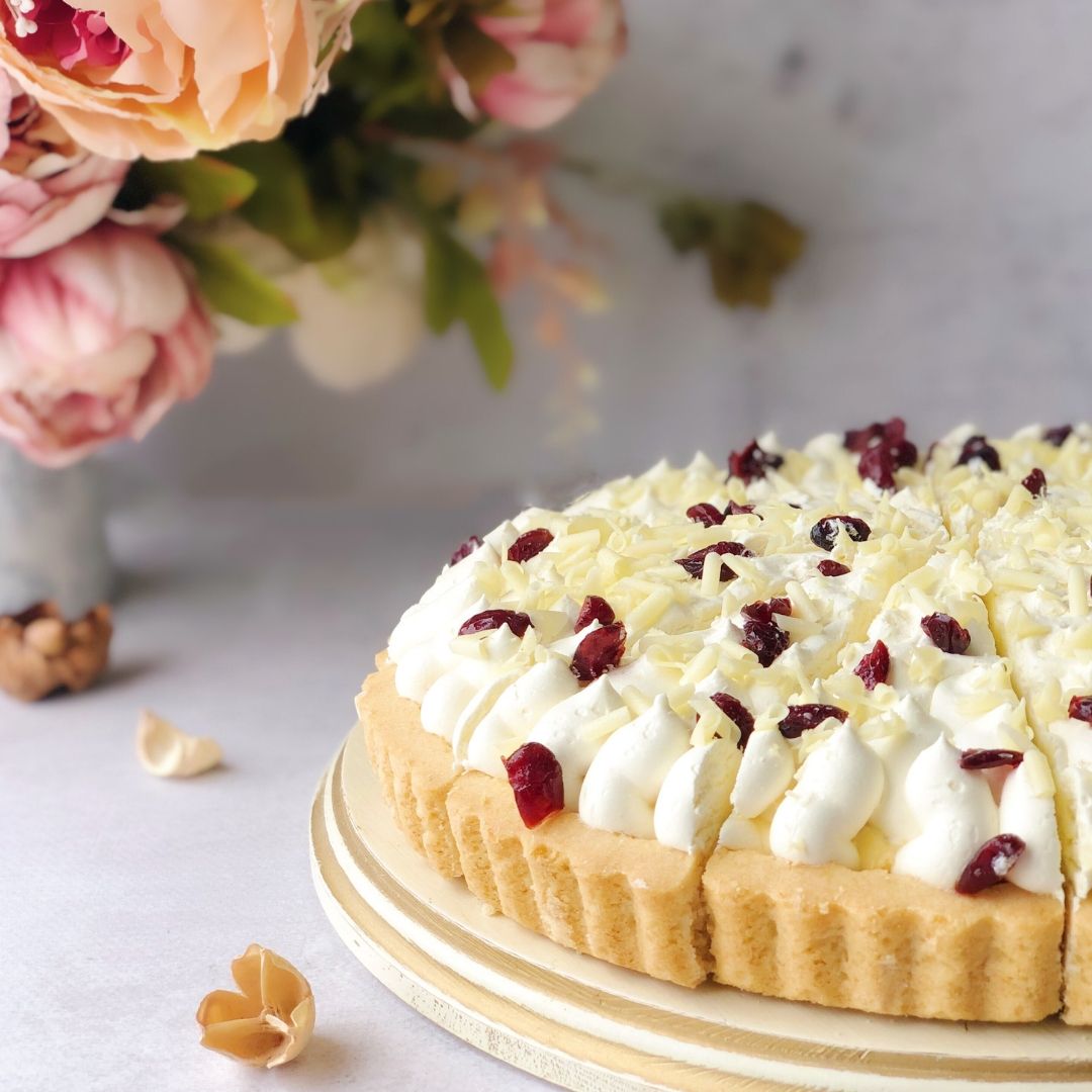 Пирог с брусничной начинкой и начинкой из белого шоколада, брусникой, взбитыми сливками, украшенный белым шоколадом и клюквой. изображение 3