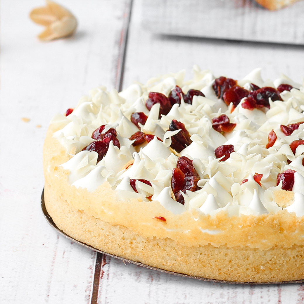 Пирог с брусничной начинкой и начинкой из белого шоколада, брусникой, взбитыми сливками, украшенный белом шоколадом и клюквой. изображение 1