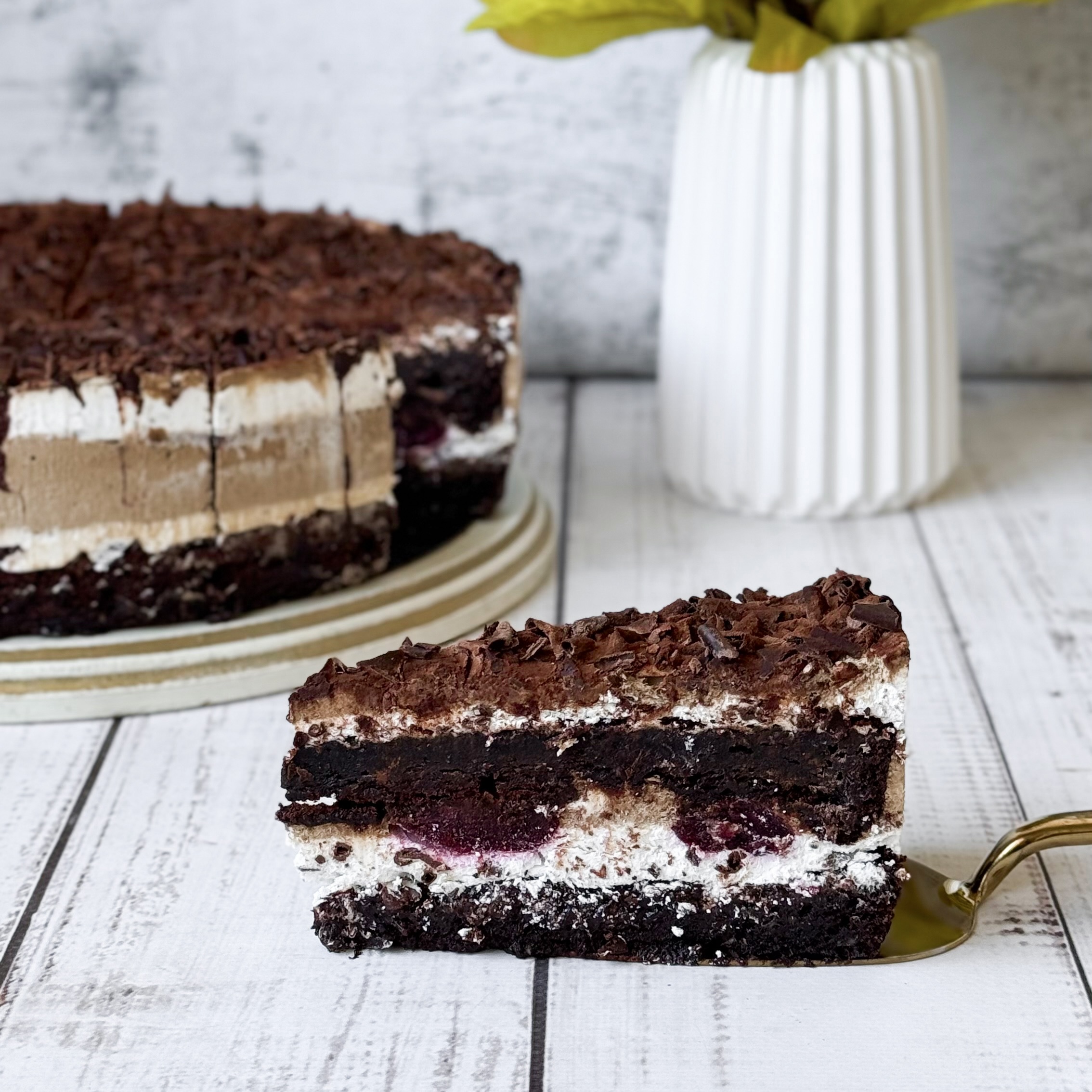 Слои шоколадного бисквита, пропитанного вишневым сиропом, чередуются со слоями крема из свежих сливок и сочных вишен. Украшен шоколадной стружкой. изображение 1