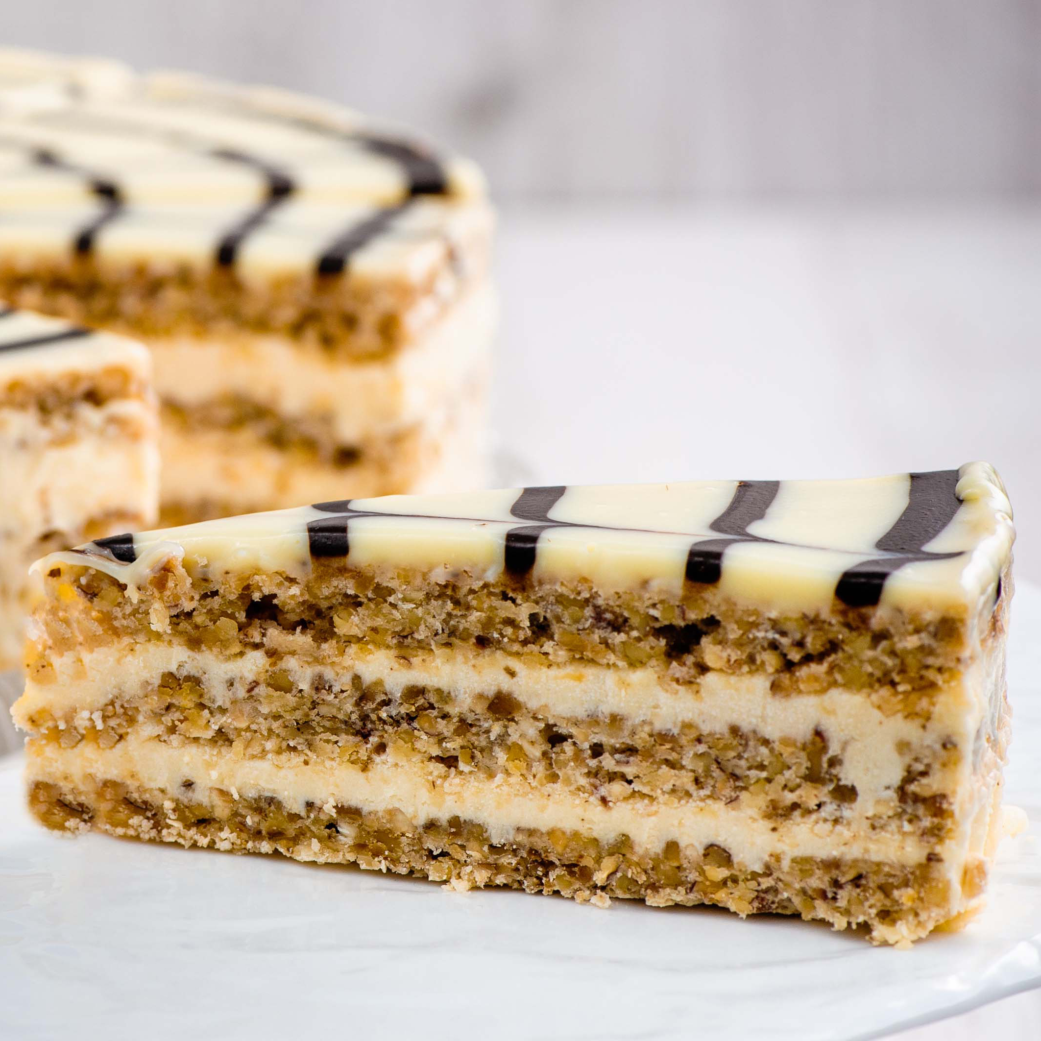 Изысканный классический торт из воздушного ванильно-орехового бисквита, щедро дополненного нежным ванильно-сливочным кремом и посыпанного дробленным орехом. Сверху украшен сахарной помадкой и классическим мраморным рисунком. изображение 4