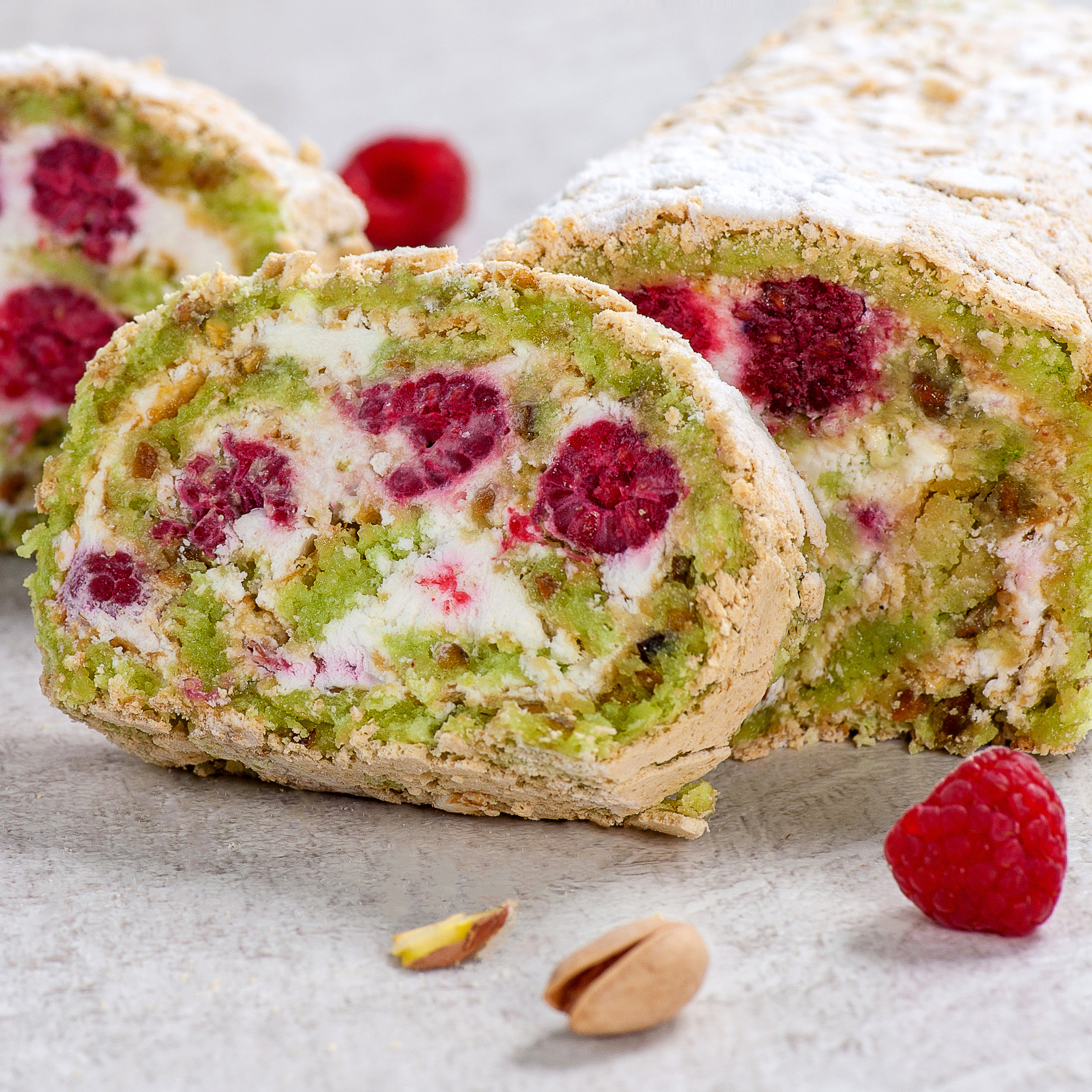 Внутри фисташкового бисквита нежный крем на основе взбитых сливок и спелая малина. Невероятно сочный вкус! Рулет украшен посыпкой из сахарной пудры. изображение 1