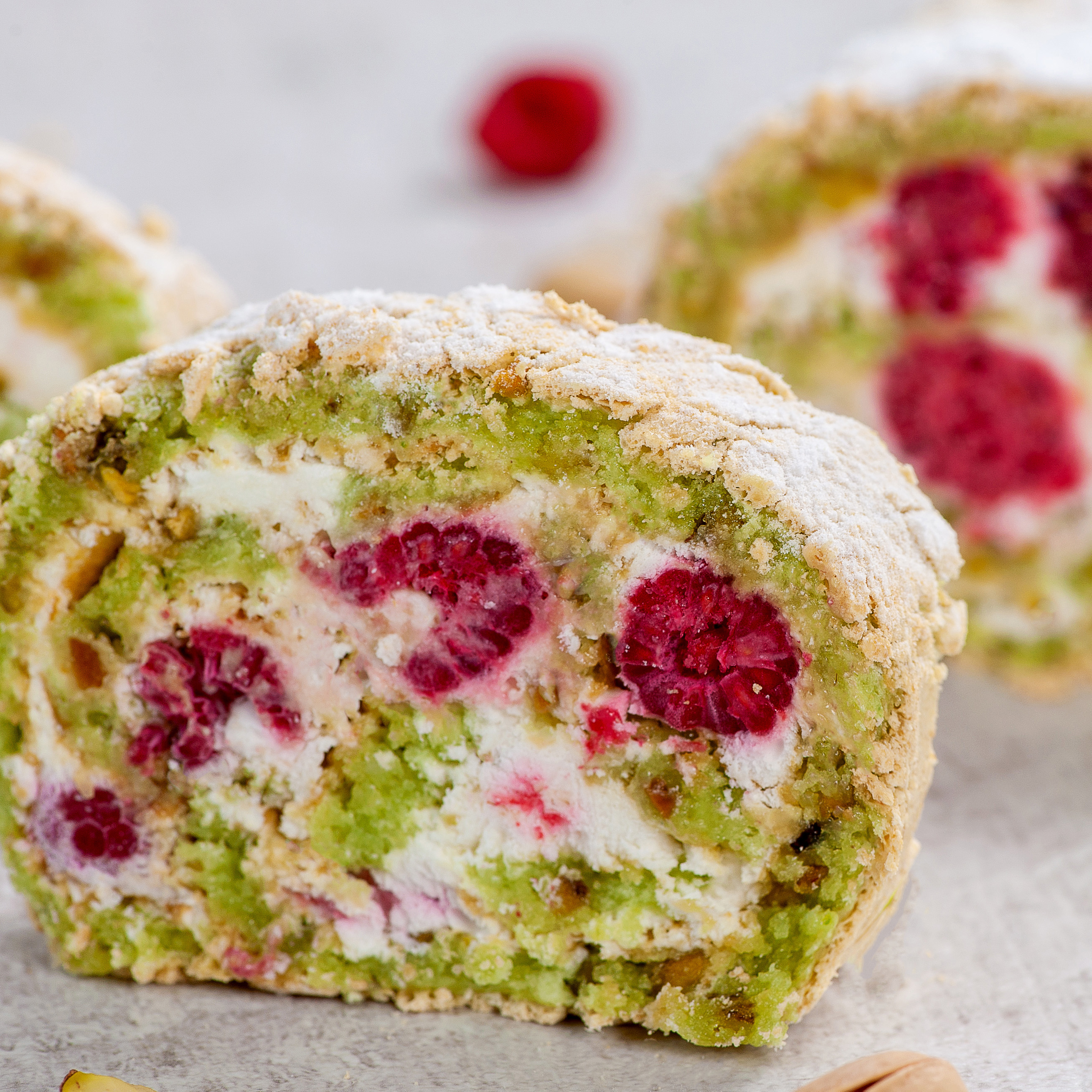 Внутри фисташкового бисквита нежный крем на основе взбитых сливок и спелая малина. Невероятно сочный вкус! Рулет украшен посыпкой из сахарной пудры. изображение 2