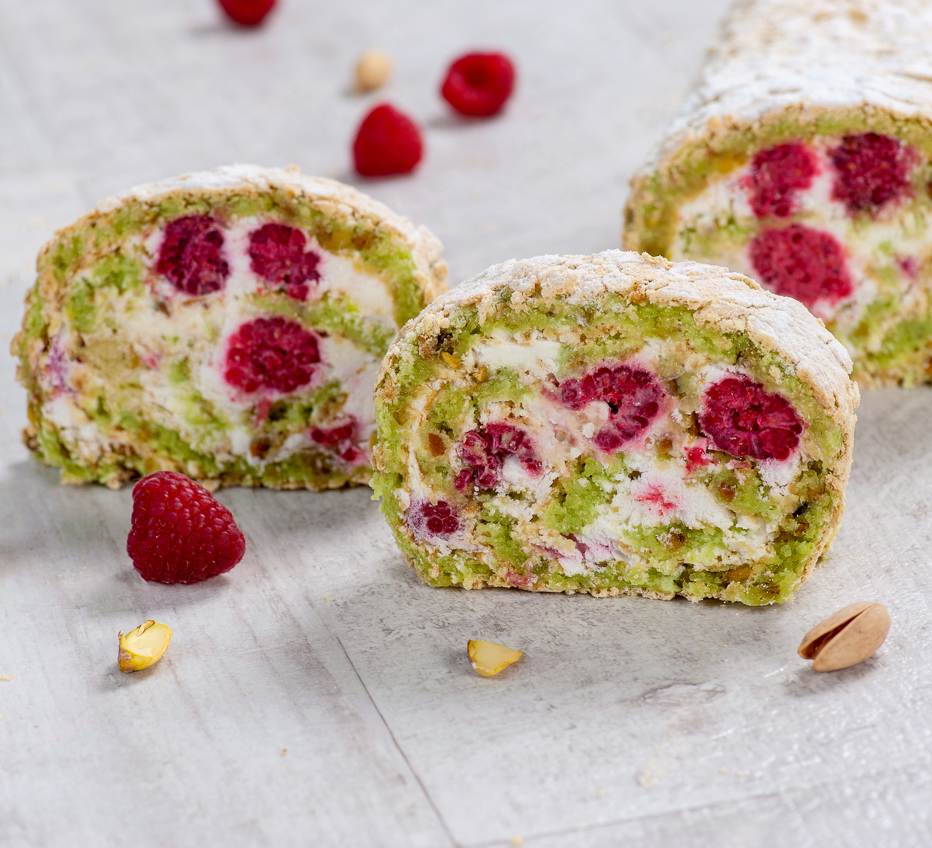 Внутри фисташкового бисквита нежный крем на основе взбитых сливок и спелая малина. Невероятно сочный вкус! Рулет украшен посыпкой из сахарной пудры. изображение 2