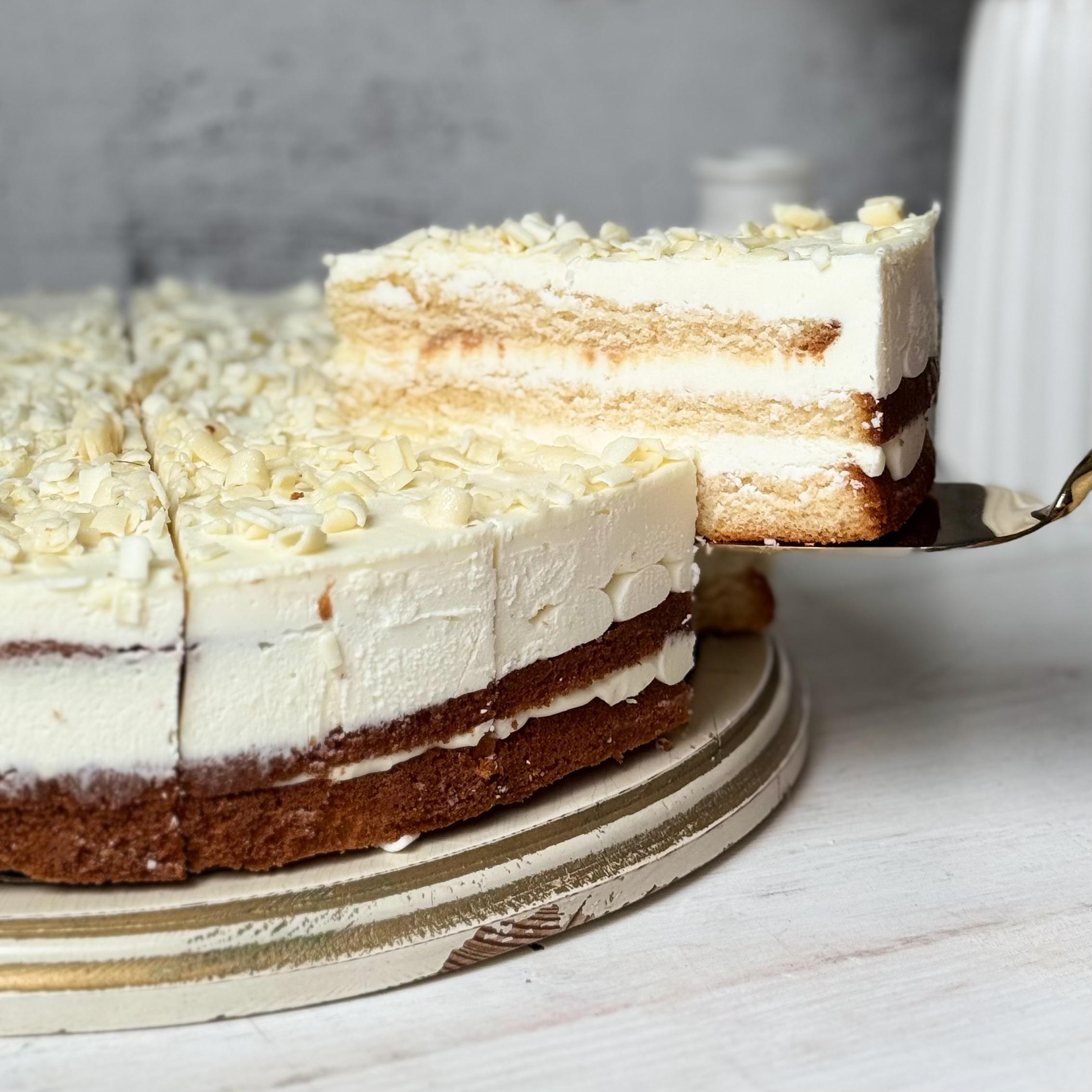 Изысканный торт из слоев нежного бисквита и творожного крема. Сверху торт украшен посыпкой из белого шоколада. изображение 1
