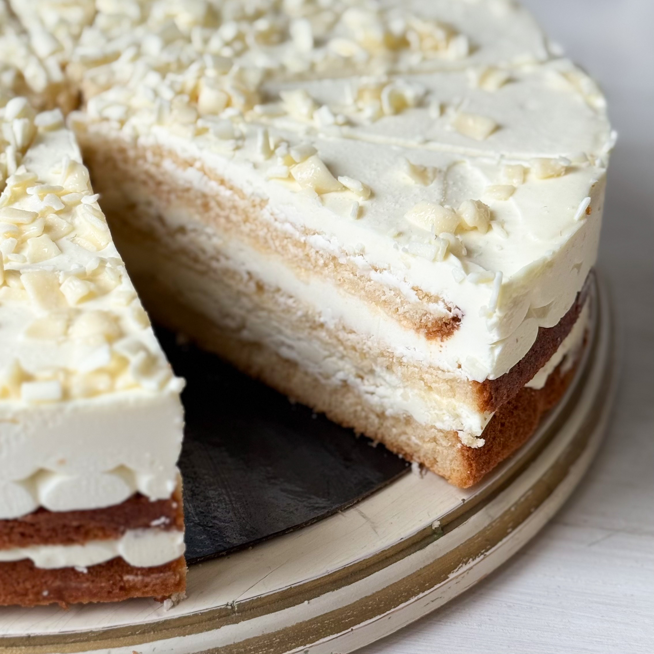 Изысканный торт из слоев нежного бисквита и творожного крема. Сверху торт украшен посыпкой из белого шоколада. изображение 11