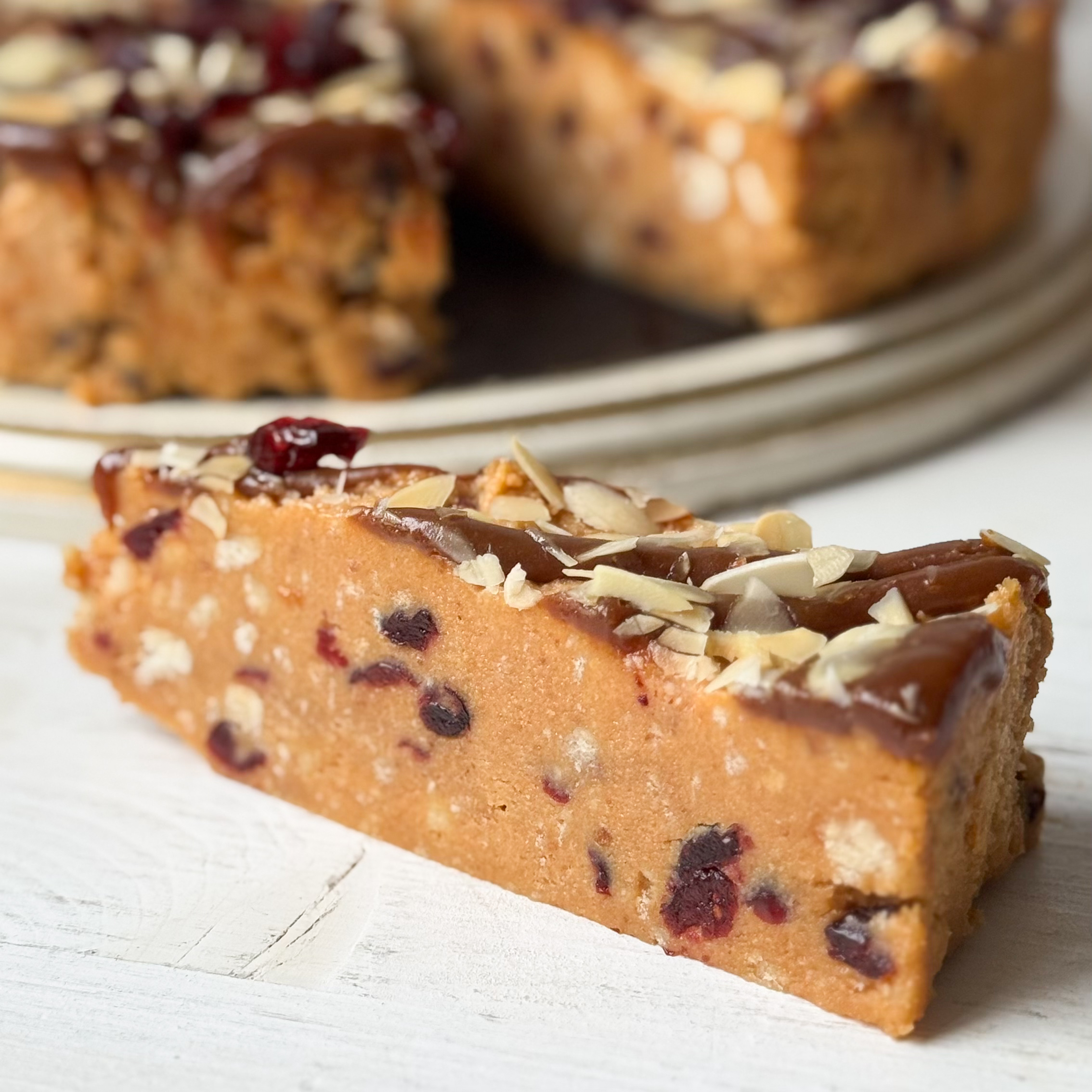 Сочный песочно-карамельный торт с сушеной клюквой и кусочками печенья. Сверху торт украшен волнами мягкой карамели, лепестками миндаля и клюквой.  изображение 2