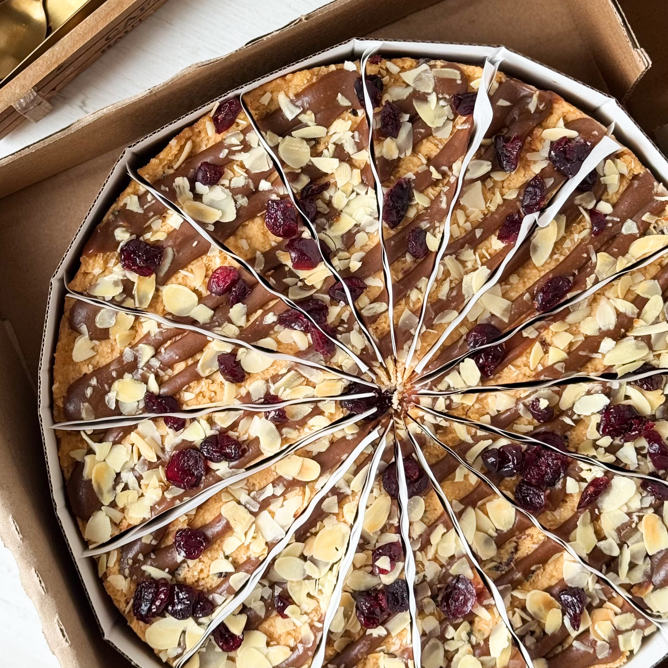 Сочный песочно-карамельный торт с сушеной клюквой и кусочками печенья. Сверху торт украшен волнами мягкой карамели, лепестками миндаля и клюквой.  изображение 3