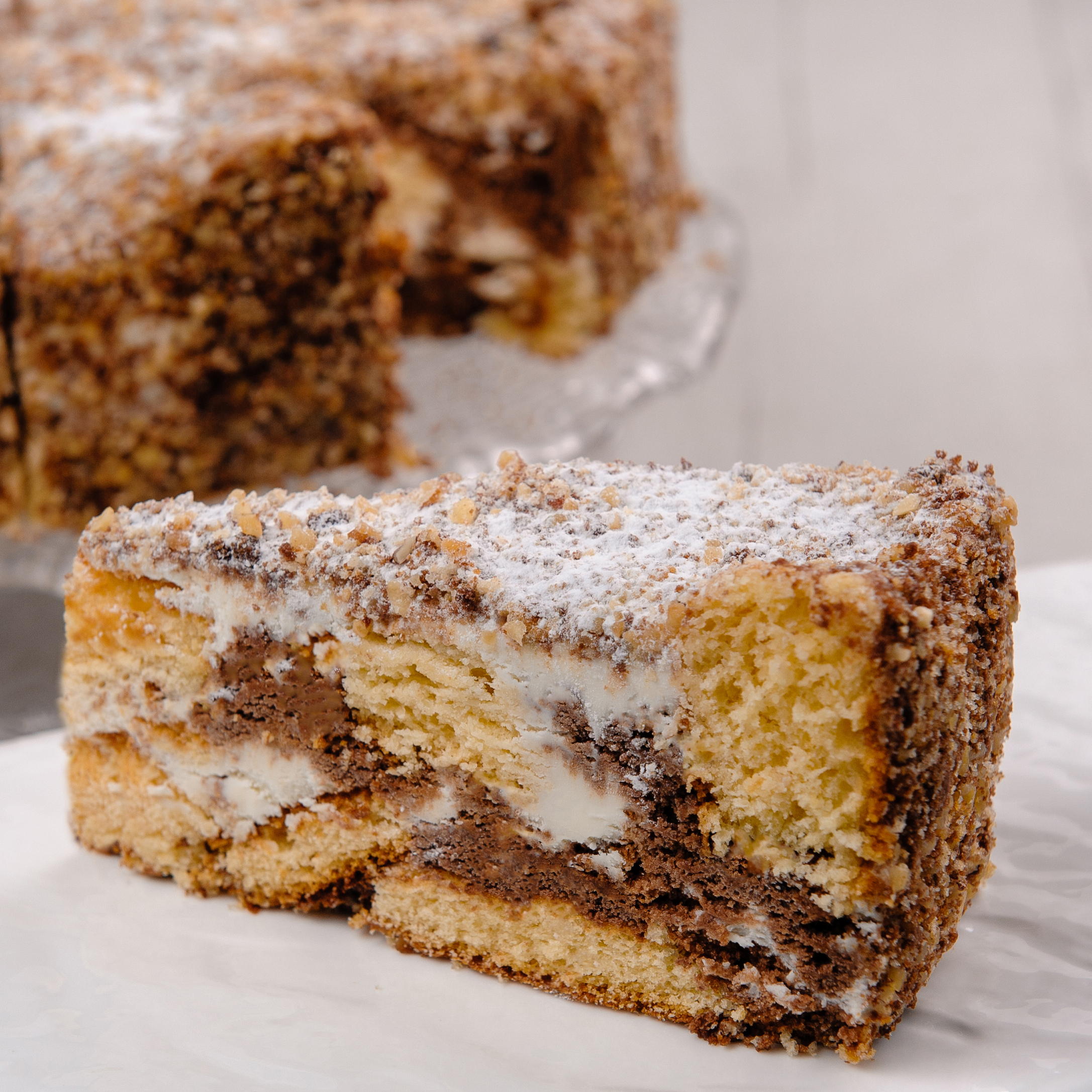 Белый и шоколадный бисквиты, прослоенные сметанным кремом. Торт украшен дроблёным орехом. изображение 4