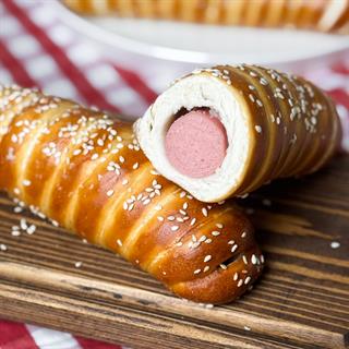 Сочная мясная сосиска и традиционное тесто для немецких брецелей. Сверху брецель-дог посыпан кунжутом.