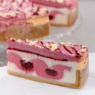 Чизкейк из творожного сыра с прослойкой из малинового мусса и малинового пюре на песочной подложке. Сверху чизкейк украшен пиками из мусса и белым шоколадом.