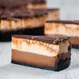 Корж из темного шоколада, горько-сладкий шоколадный чизкейк, чизкейк из молочного шоколада. Украшен глазурью из темного шоколада и полит молочным шоколадом.