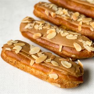 Карамельный эклер с кремом из взбитых сливок с карамелью, украшенный лепестками миндаля