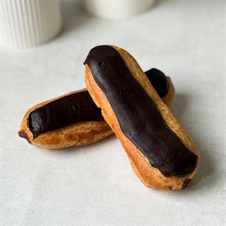 Шоколадный эклер с кремом из взбитых сливок с шоколадом, украшенный шоколадной помадкой