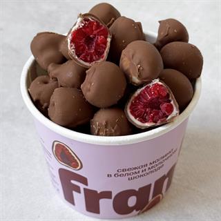 Нежные ягоды малины, покрытые слоями белого и молочного шоколада