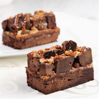 Два слоя сочного шоколадного брауни, пропитанные густой карамелью, сверху украшены засахаренными кусочками брауни и грецкими орехами.