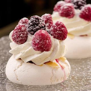 Воздушное безе с вишнёвой сердцевиной, прослойкой из лепестков миндаля и сливочным кремом. Сверху украшено свежими ягодами малины.