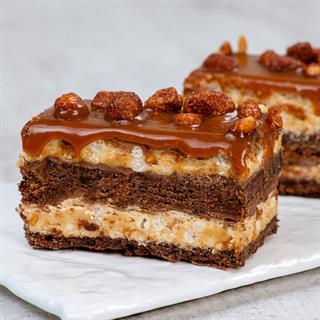 Классический брауни со слоями сливочной карамели, пралине и молочного шоколада. Сверху пирожное украшено карамелизированным арахисом и залит плотным слоем мягкой карамели