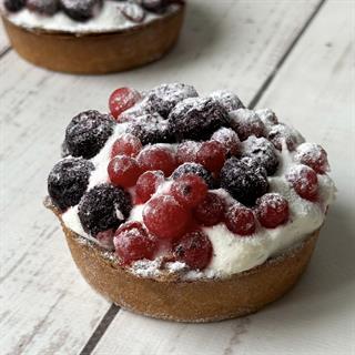 Ягодная тарталетка с начинкой из пюре чёрной смородины, взбитыми сливками и ягодами чёрной смородины в корзиночке из песочного теста.