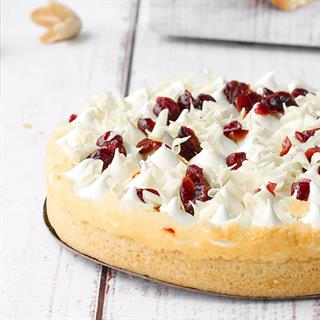 Пирог с брусничной начинкой и начинкой из белого шоколада, брусникой, взбитыми сливками, украшенный белом шоколадом и клюквой.