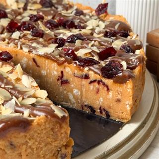 Сочный песочно-карамельный торт с сушеной клюквой и кусочками печенья. Сверху торт украшен волнами мягкой карамели, лепестками миндаля и клюквой. 